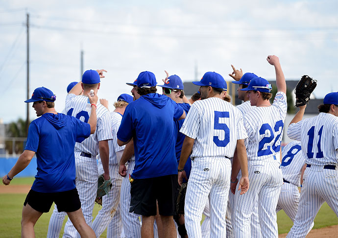 Baseball players and coaches celebrate together on field