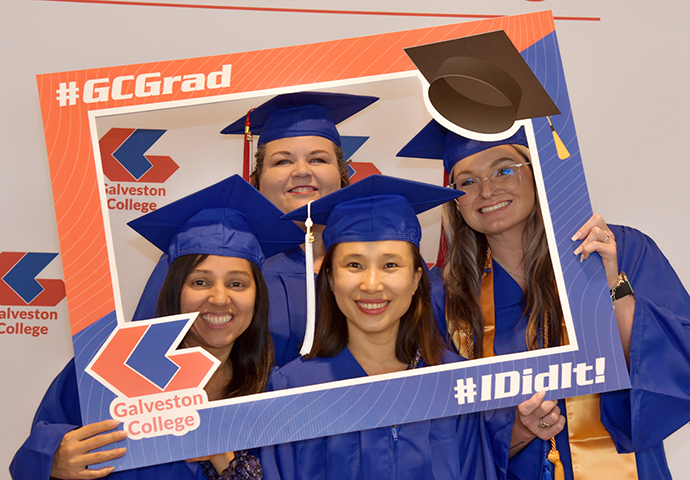 Four graduates pose with frame.