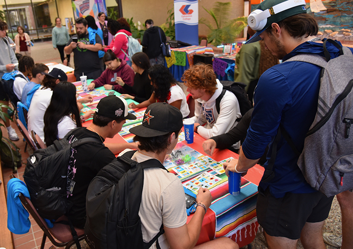 Students gather around a table playing games.