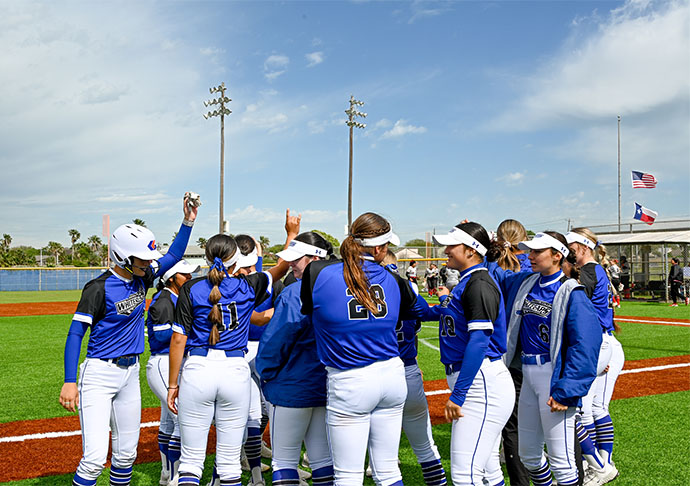 Softball players celebrate together on field