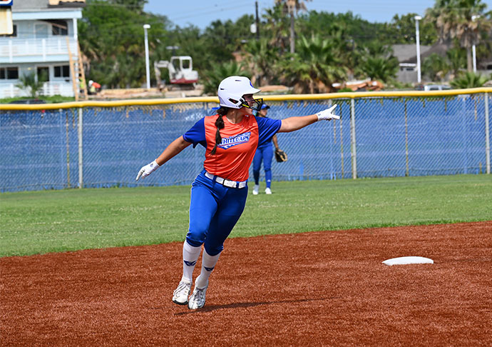 Softball player runs bases while pointing