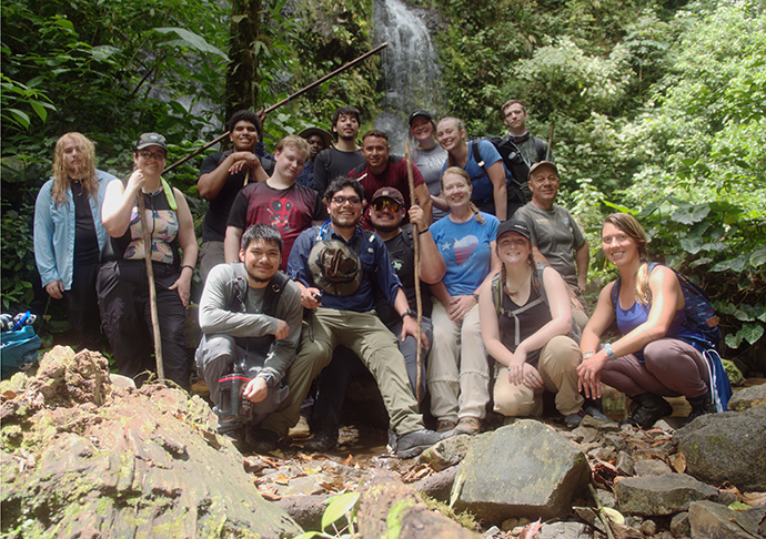 A group of students pose by a waterfall in Costa Rica.