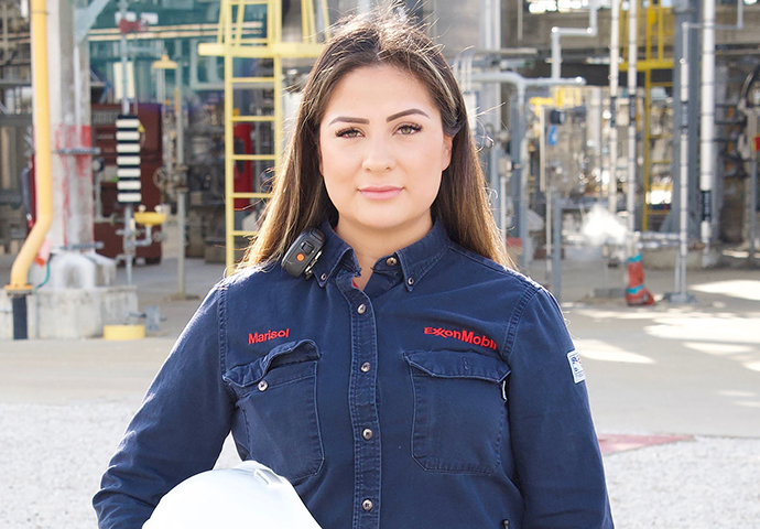 Woman stands in Exxon Mobile uniform with safety helmet.